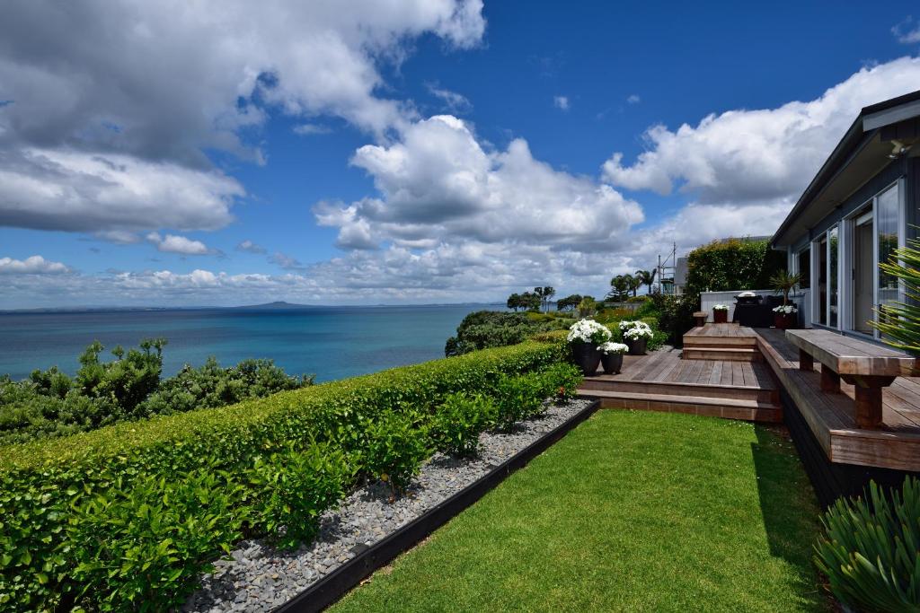 un jardín con un banco y vistas al océano en Luxury house with Clifftop Seaview, en Whangaparaoa