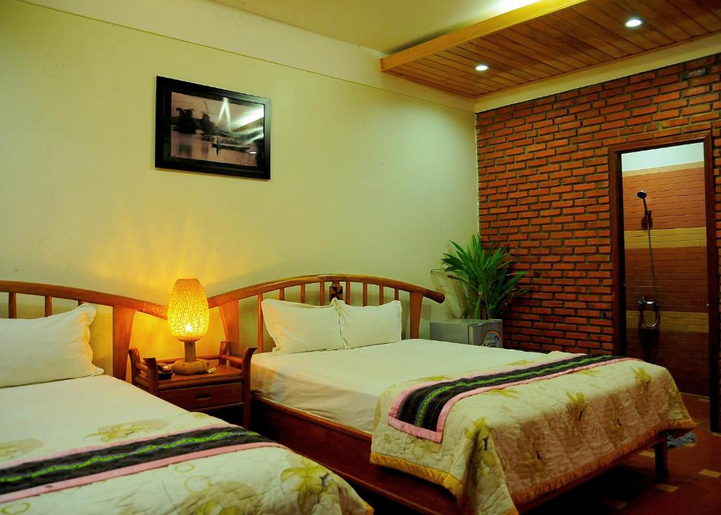 Kon Tum (2)にあるKhách Sạn Xanh hotelのベッド2台と窓が備わるホテルルームです。