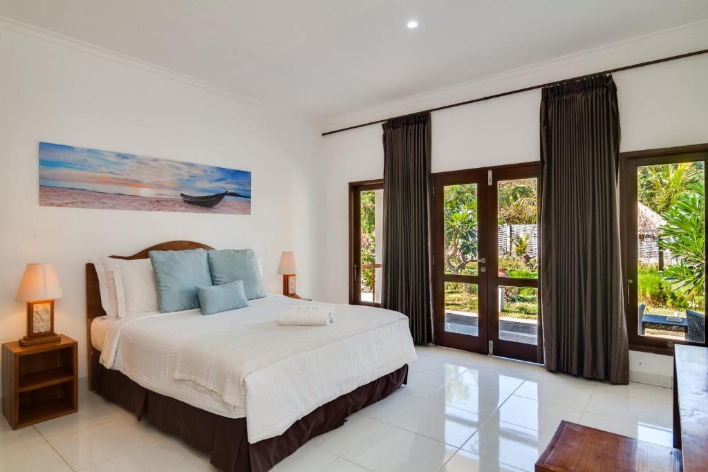 a bedroom with a large bed and large windows at Blue Marine Resort in Gili Islands