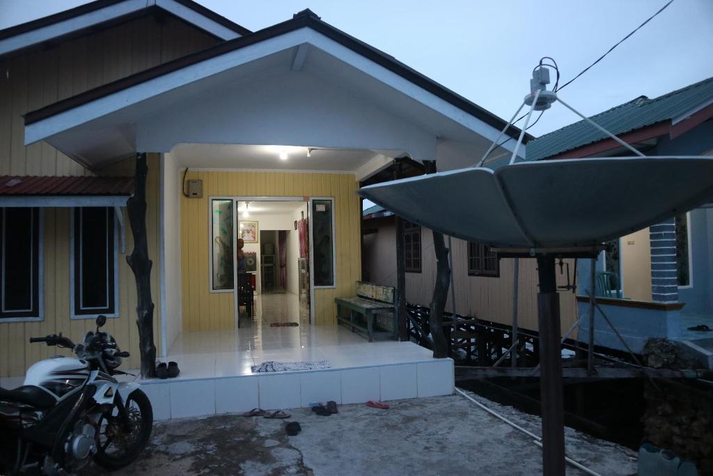 a house with a motorcycle parked in front of it at Homestay Tanjung Duata Bohe Silian in Maratua Atoll