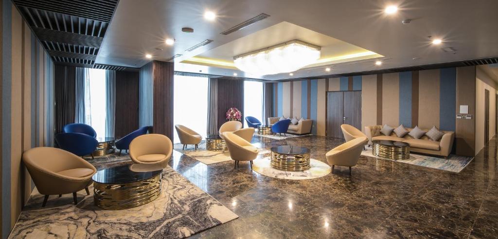 A spacious lobby lounge with varied armchairs, low tables, and a polished marble-look floor.
