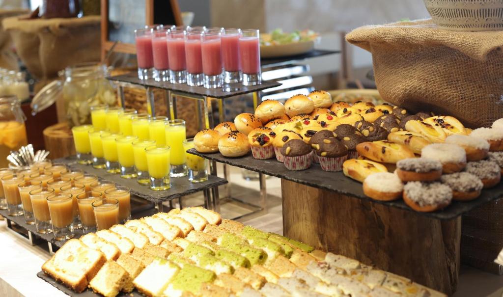 A pastry-and-drinks station with juices, muffins, small cakes and sliced loaves.