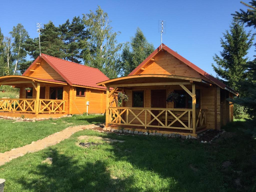 a log cabin with a red roof at Domki W Sercu Mazur in Ryn