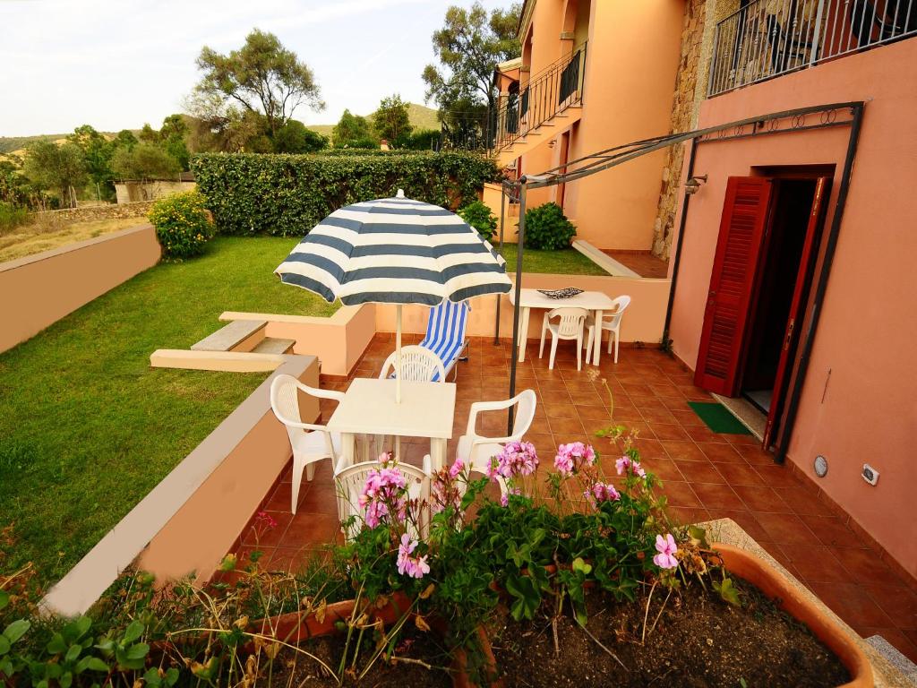 un patio con tavolo, sedie e ombrellone di B&B Simon&Simon a San Teodoro