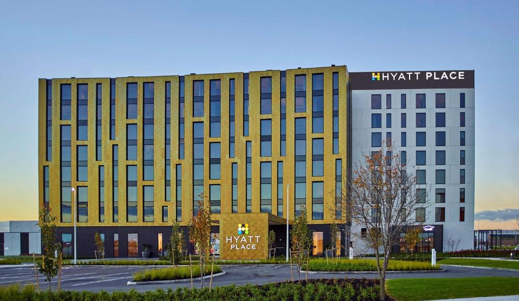 Hyatt Place Melbourne Essendon Fields في ملبورن: مبنى اصفر كبير عليه لافته