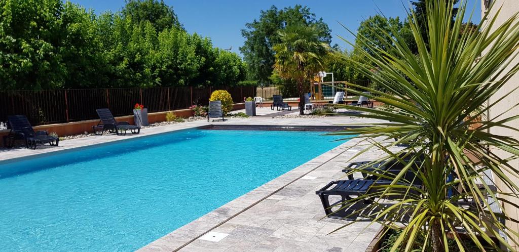 a swimming pool with chairs and a palm tree next to it at Logis Hotel Archambeau in Thonac