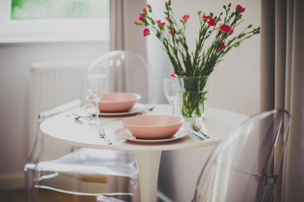 Una mesa con dos platos y un jarrón de flores. en Apartament Słoneczny, en Uniejów