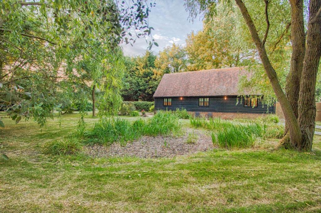 a wooden barn in the middle of a field at Highgate Annexe in Takeley