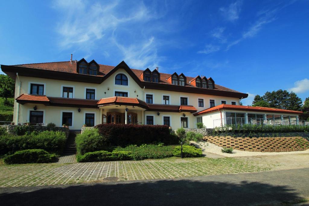 duży biały dom z czerwonym dachem w obiekcie Aquilo Hotel Panoráma w Tihany