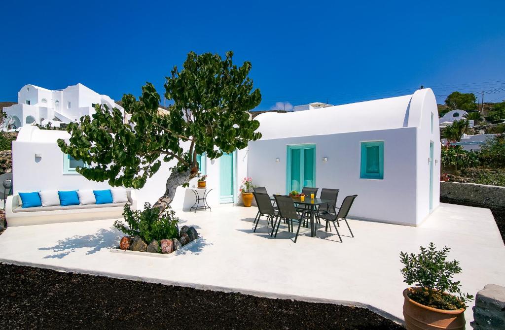 a villa with a tree and a table and chairs at Mulberry Villa in Oia