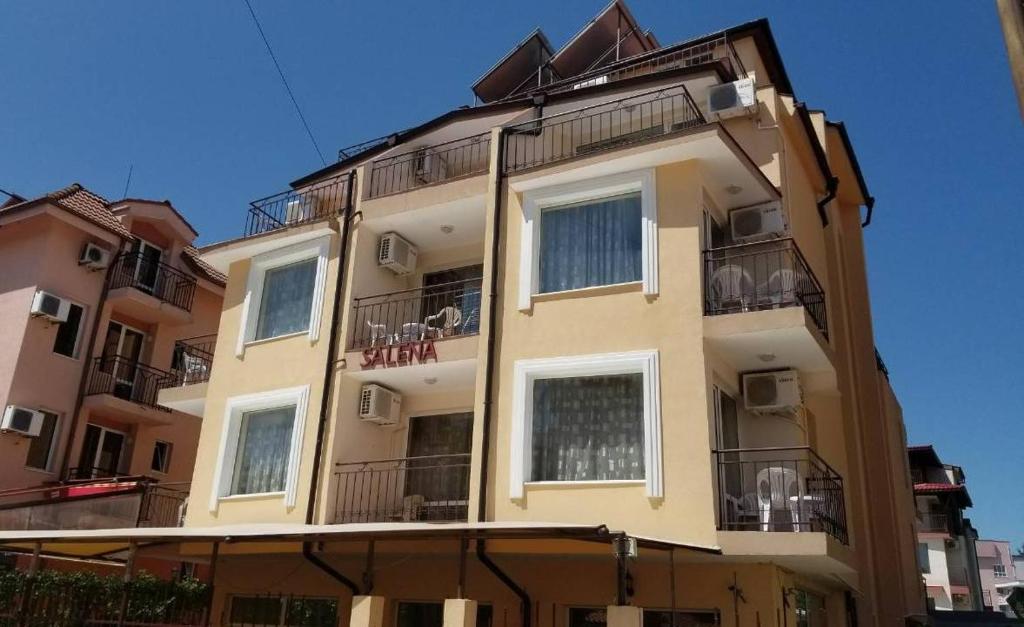 un edificio alto de color amarillo con ventanas y balcones en Salena Hotel, en Primorsko