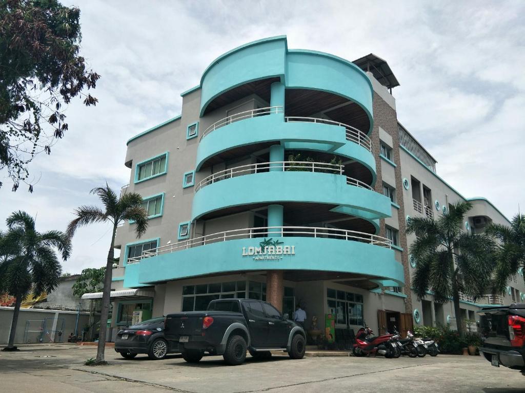 ein blaues Gebäude mit einem davor geparkt in der Unterkunft Lomsabai Apartments in Bangsaen