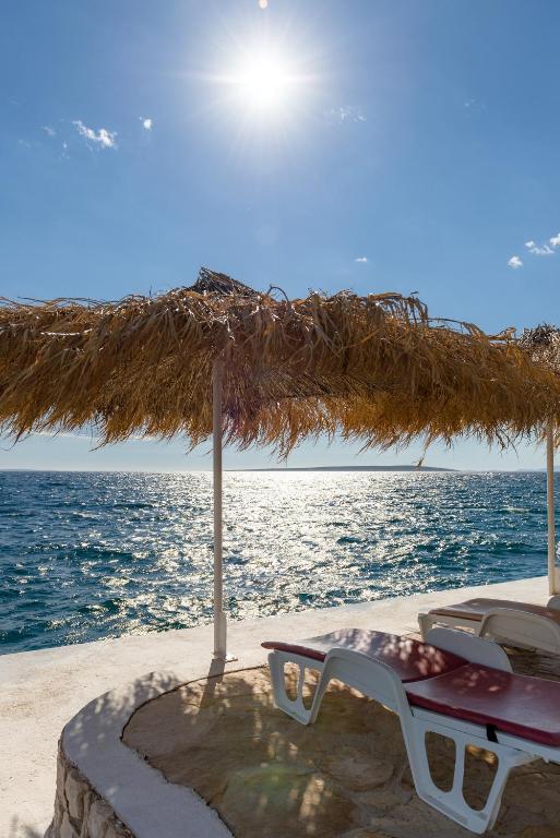 a table and chairs under a straw umbrella on the beach at Holiday Park Mandrice in Mandre