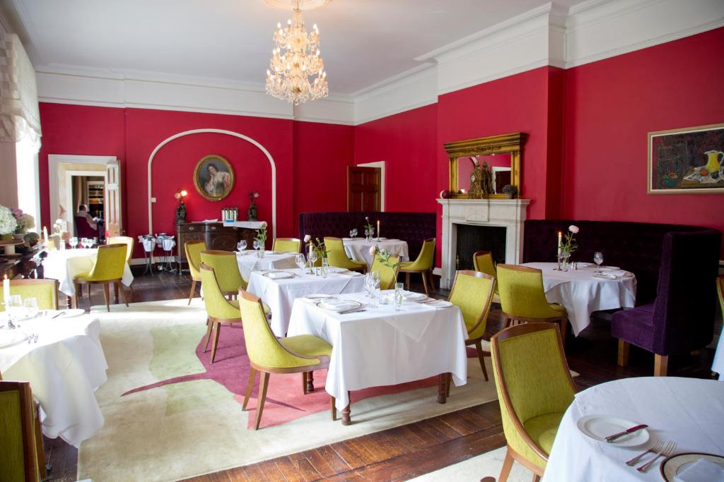 uma sala de jantar com mesas brancas e cadeiras amarelas em Dunbrody Country House Hotel em Arthurstown