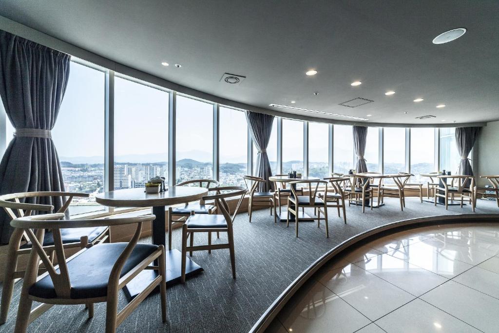 un restaurante con mesas, sillas y ventanas grandes en Gangneung Tourist Hotel, en Gangneung