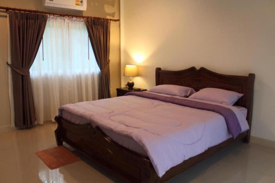 a bedroom with a large bed and a window at Baan Suan Nam Resort in Don Sak
