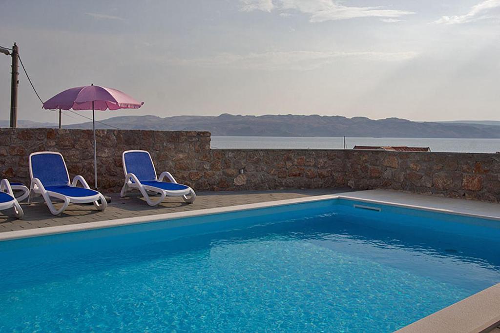 uma piscina com duas cadeiras e um guarda-sol em Apartment Annabella with Pool and sea view em Karlobag