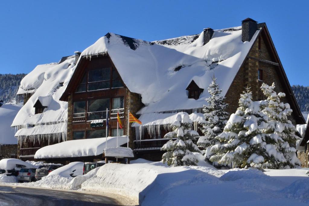 バケイラ・ベレットにあるHotel Chalet Bassibeの屋根に雪が積もった丸太キャビン