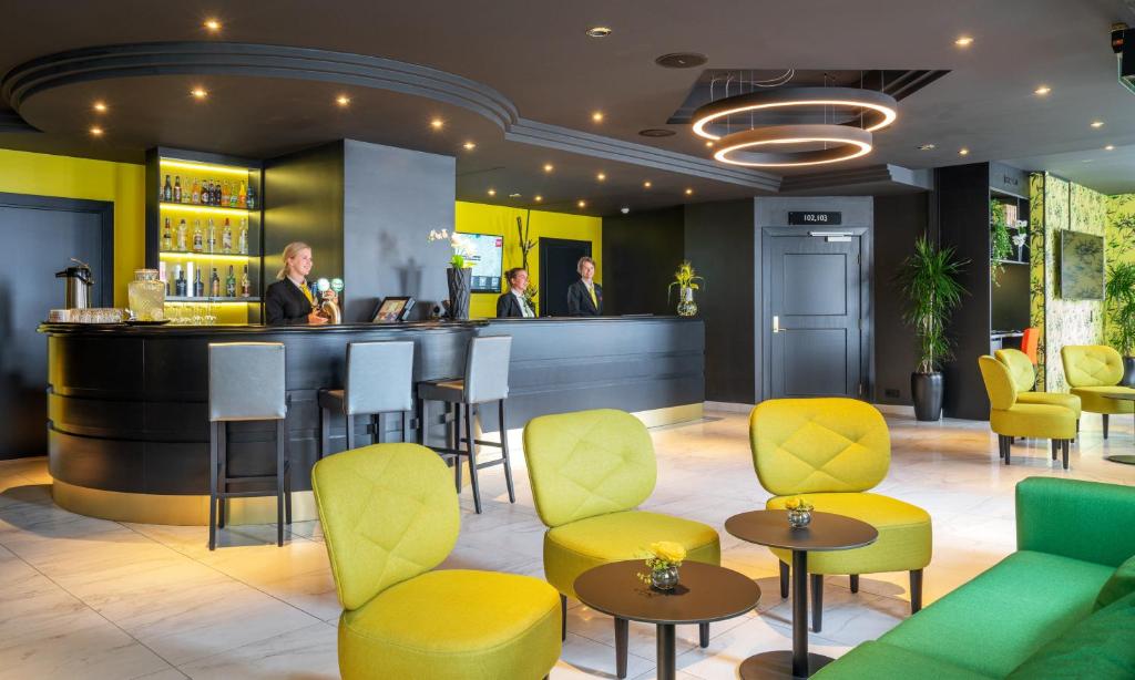 a bar in a restaurant with yellow and green chairs at Thon Hotel Moldefjord in Molde