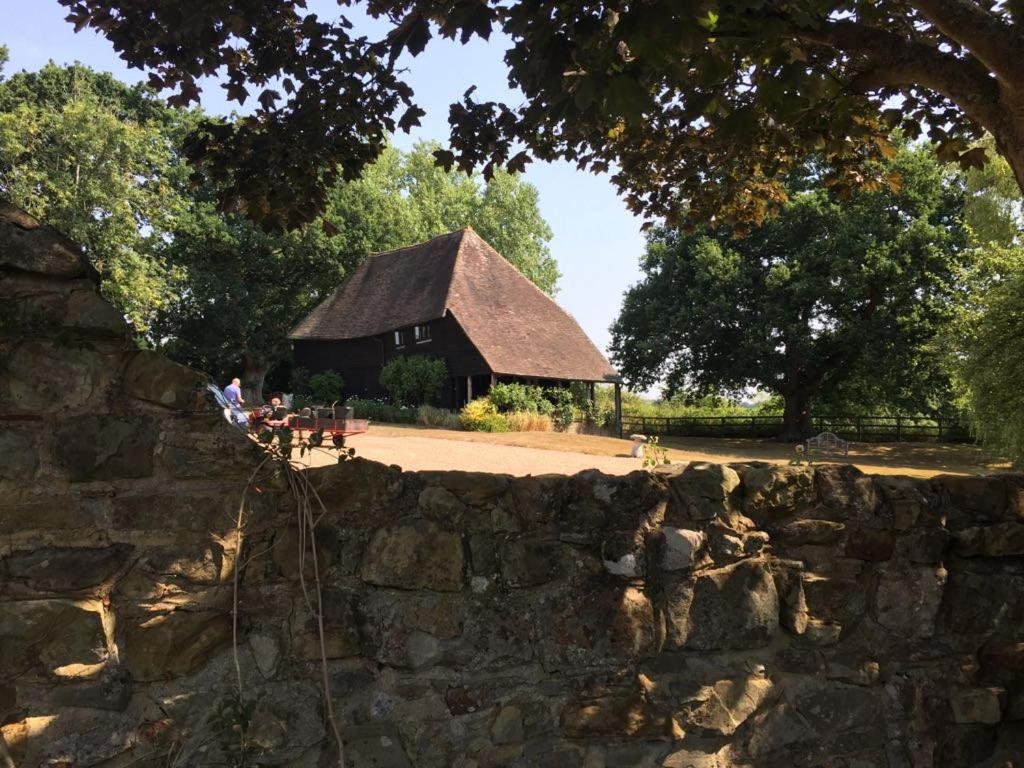 een stenen muur met een gebouw op de achtergrond bij Paul's Farmhouse in Hawkhurst