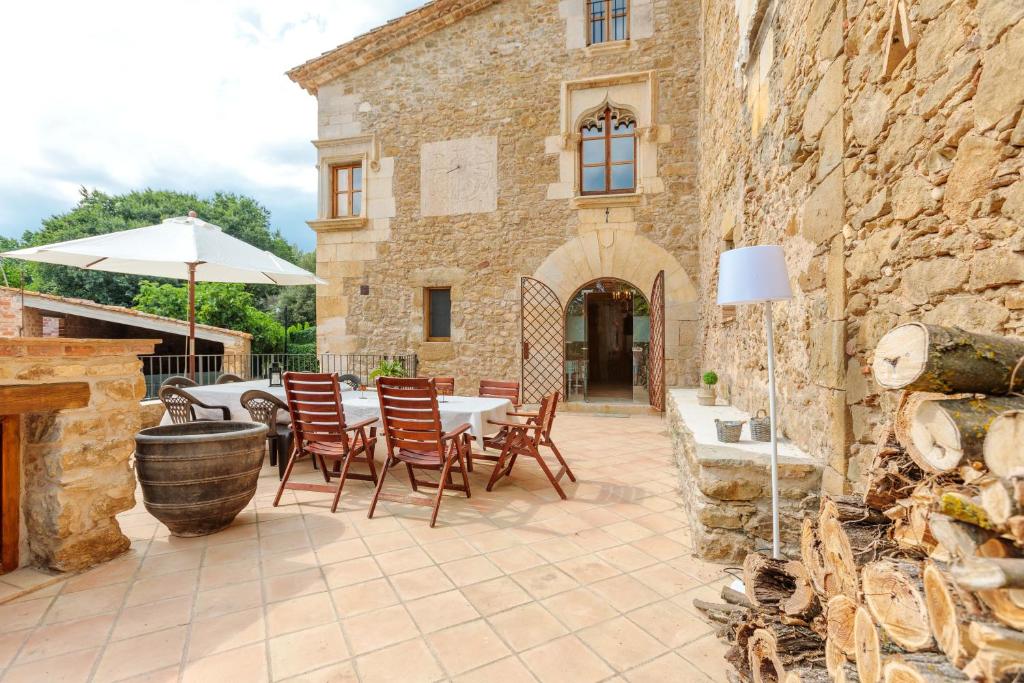 een patio met een tafel en stoelen en een parasol bij Flateli Diana in Sant Jordi Desvalls