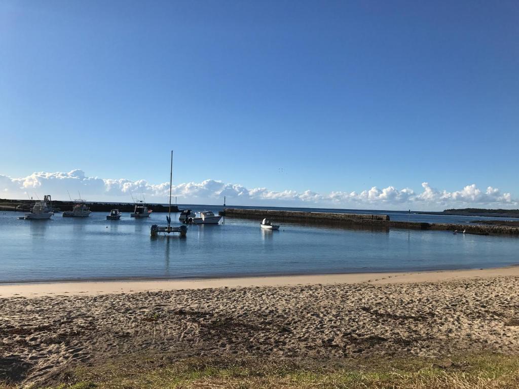 a group of boats in the water near a beach at Pelicans Rest Shellharbour in Shellharbour