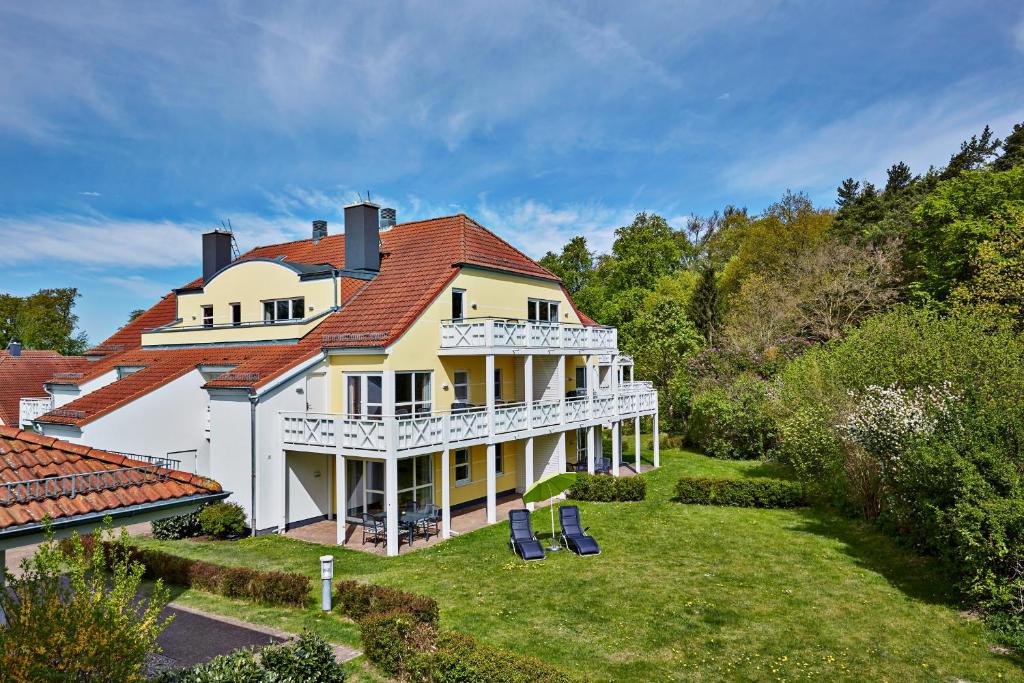 une grande maison blanche avec un toit rouge dans l'établissement H+ Hotel Ferienpark Usedom, à Ostseebad Koserow