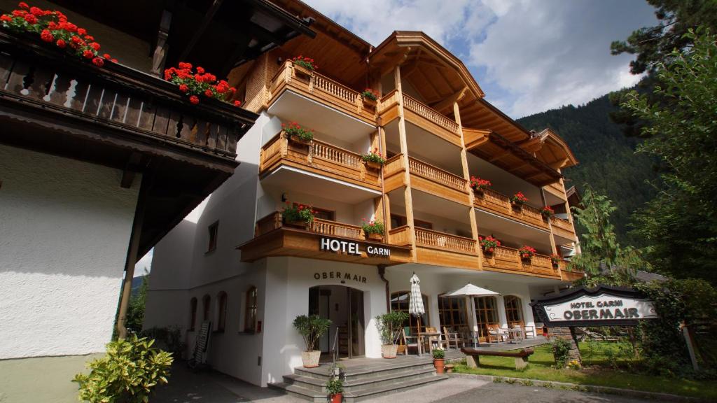 un edificio de hotel con balcón y flores. en Hotel Garni Obermair en Mayrhofen