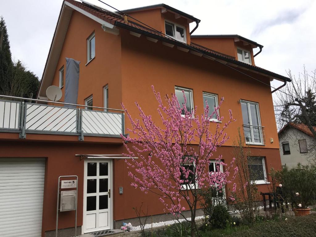 a orange house with a pink tree in front of it at Appartement Weinrebe in Wilsdruff