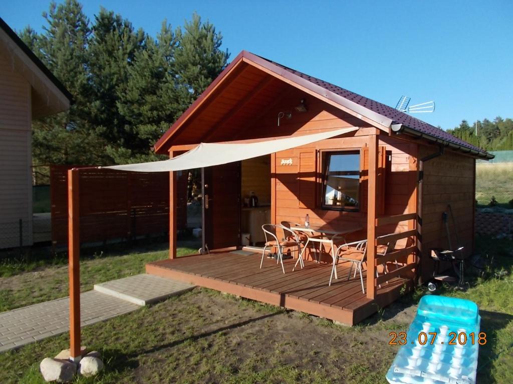 een hut met een terras met een tafel en stoelen bij Niewygodny Domek z własnym podwórkiem in Wisełka