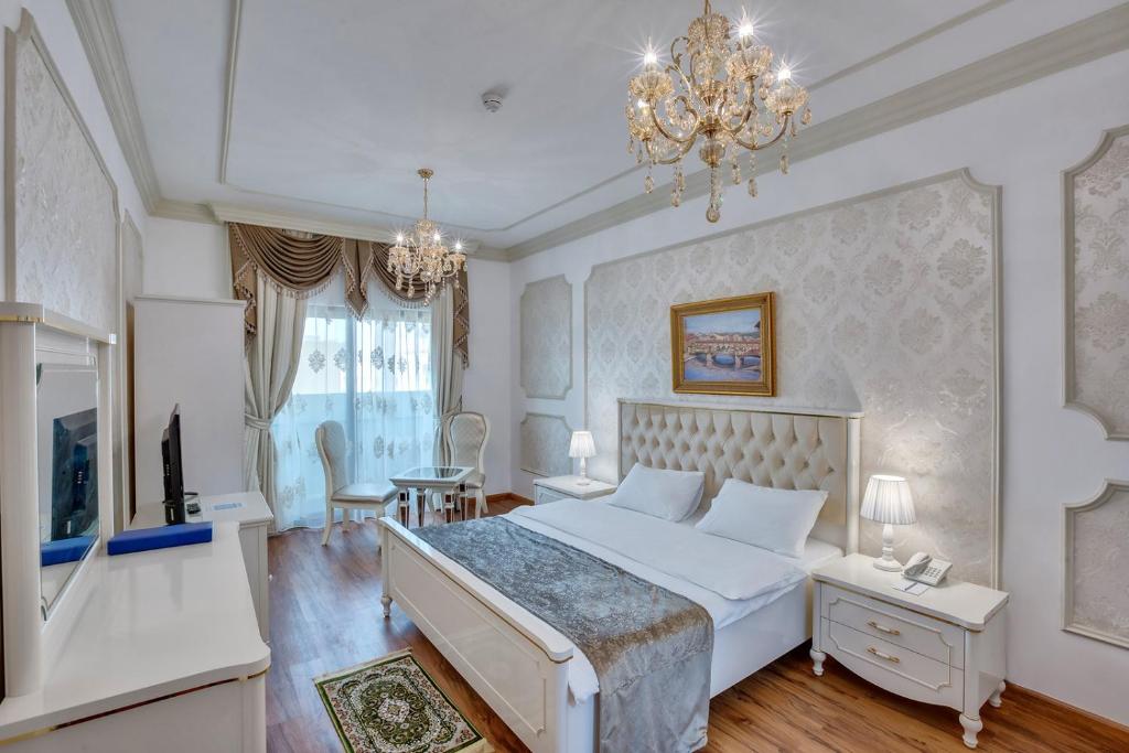 - une chambre avec un grand lit blanc et un lustre dans l'établissement Royal Hotel, à Charjah
