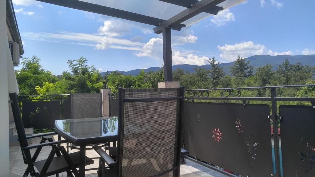 a balcony with a glass table and a view of the mountains at Apartmani Roberta in Jurdani
