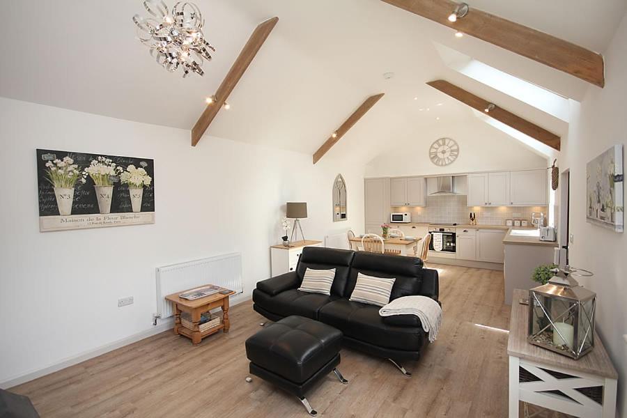 a living room with a black couch and a kitchen at The Old Stables in Taunton