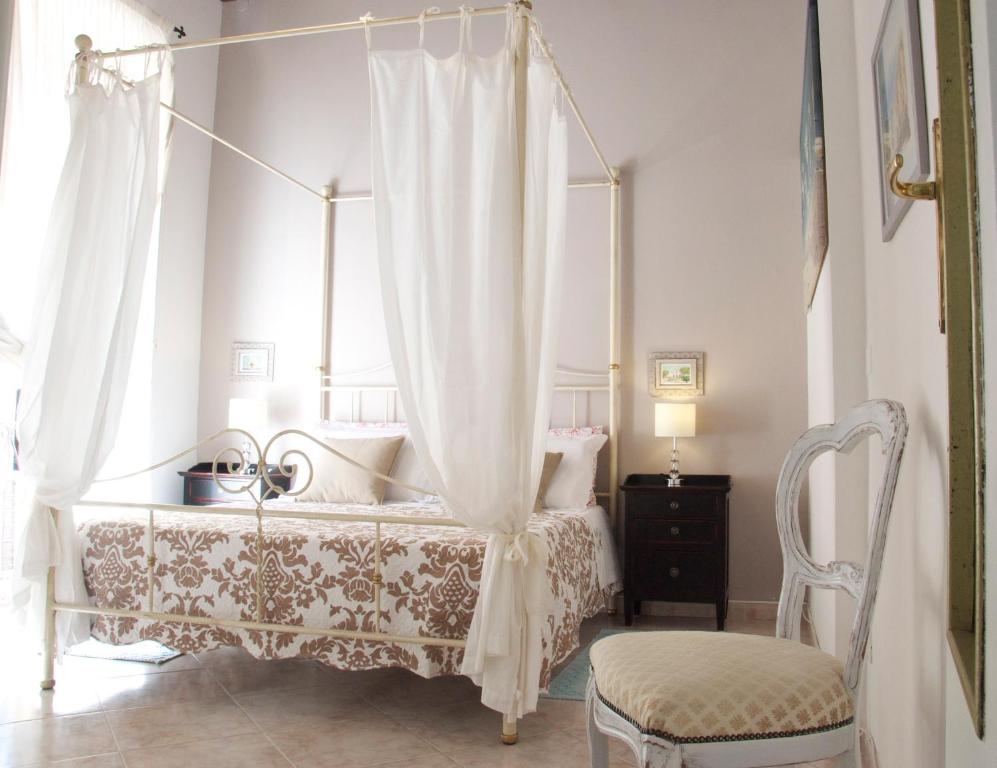 um quarto com uma cama de dossel e uma cadeira em New Romantic Suite em Cagliari