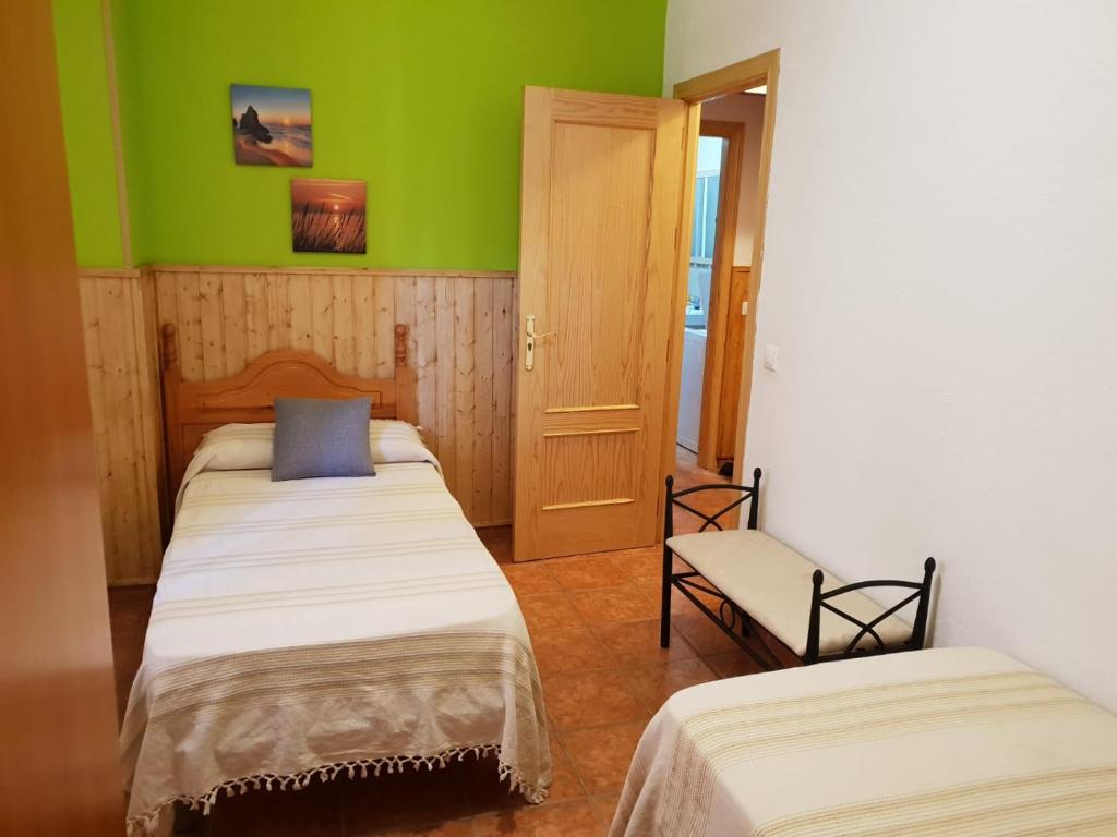 2 camas en una habitación con paredes verdes en Alojamiento Alarcon, en Arroyo Frío