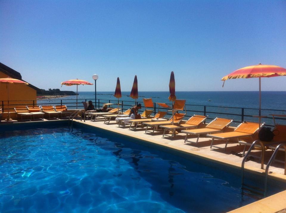 a swimming pool with chairs and umbrellas next to the ocean at Grand Hotel Dei Cesari Dependance in Anzio