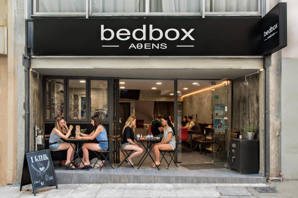 
people are sitting outside of a store at Bedbox Hostel in Athens
