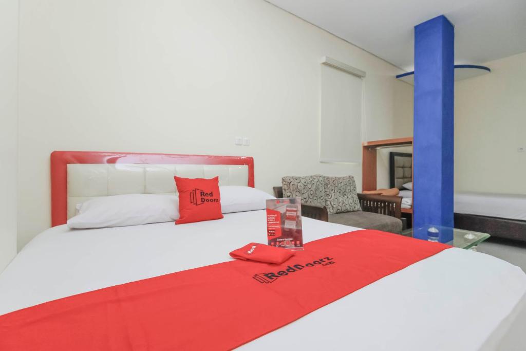 a bedroom with a bed with a red blanket on it at RedDoorz Plus @ Jalan Pemuda Jakarta in Jakarta