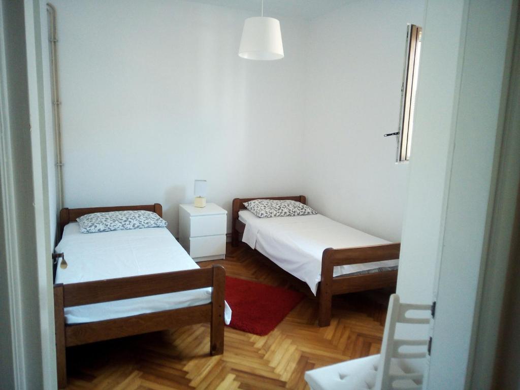 2 łóżka w małym pokoju z białymi ścianami w obiekcie Apartments Mirela w mieście Novigrad