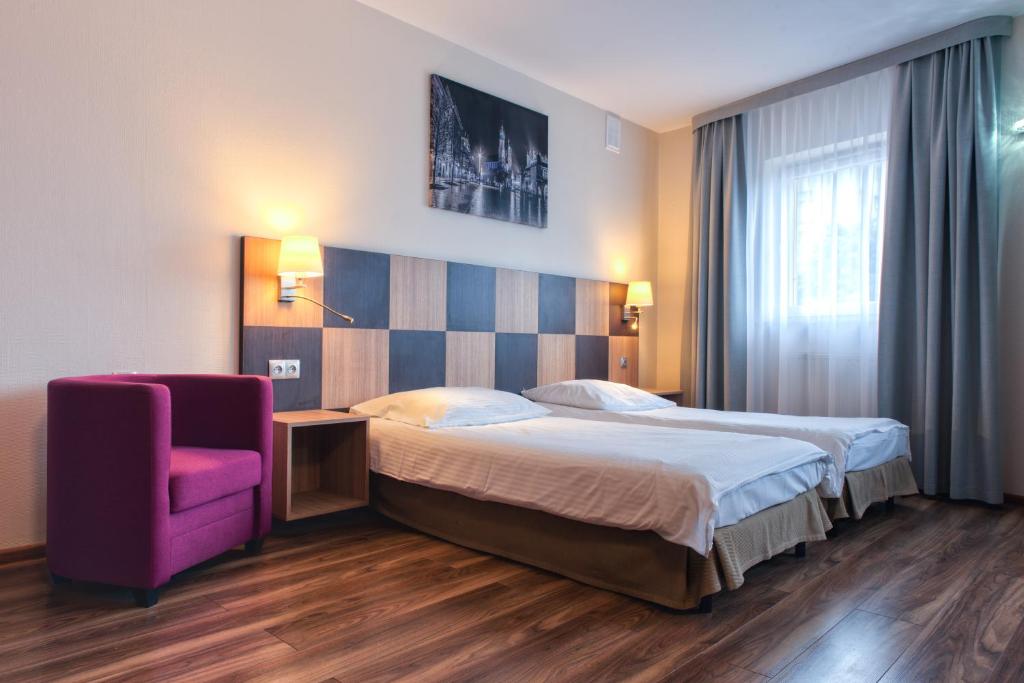 Pokój hotelowy z łóżkiem i fioletowym krzesłem w obiekcie Hotel Major Budget w Krakowie
