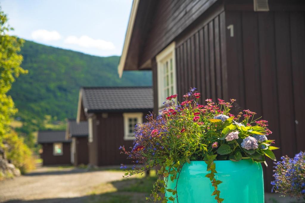 un jarrón azul lleno de flores delante de una casa en Vågåvatnet Feriesenter en Vågåmo