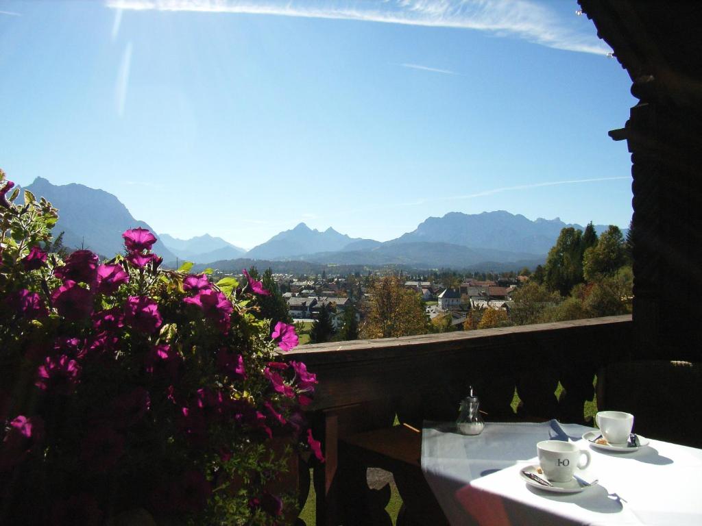 a table and flowers on a balcony with a view at Panoramahotel Karwendelhof in Wallgau