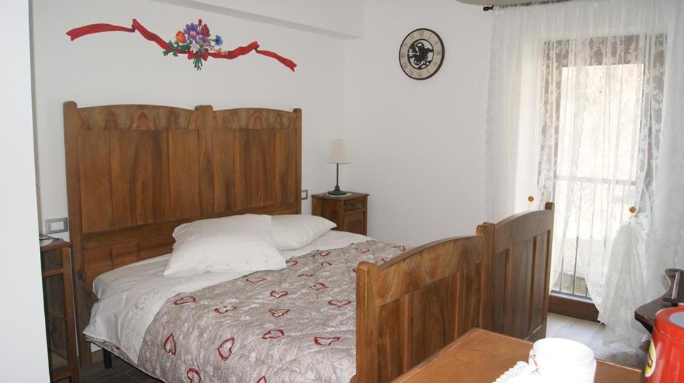 - une chambre avec un grand lit et une tête de lit en bois dans l'établissement La Tana del Ghiro Locazione Turistica, à Sedico
