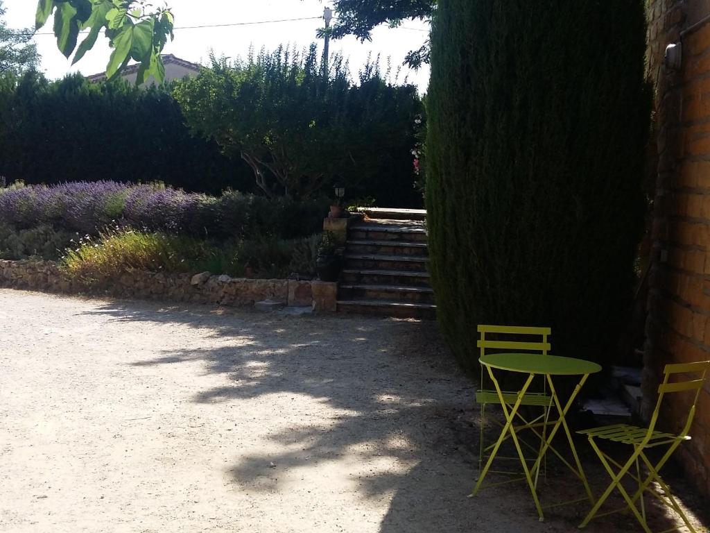 カルパントラにあるles oliviersの木の横の黄色い椅子2脚とテーブル