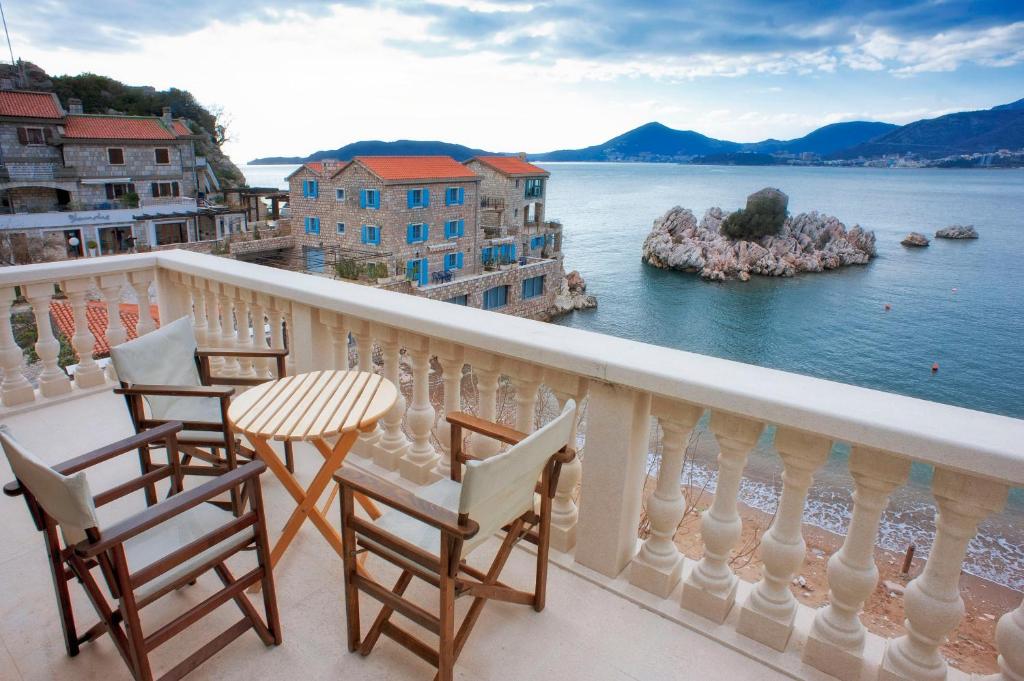 a balcony with chairs and a table and a view of the water at Pržno Luxury Apartments in Sveti Stefan