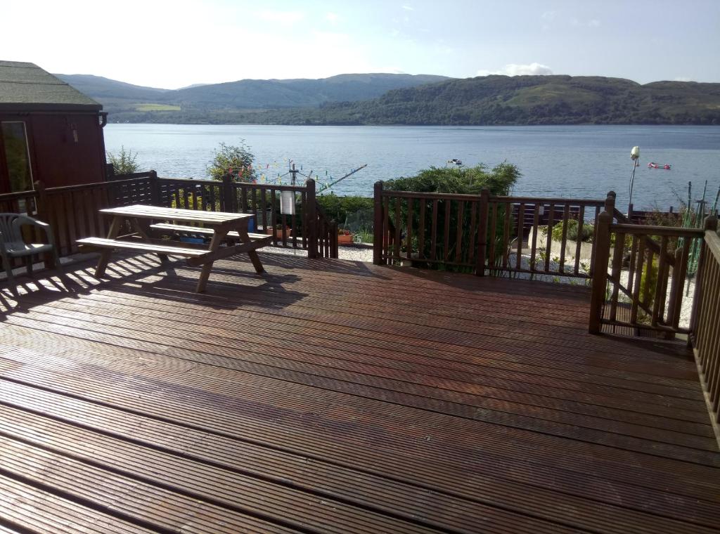 a wooden deck with a bench and a view of a lake at Maggie's in Inveraray