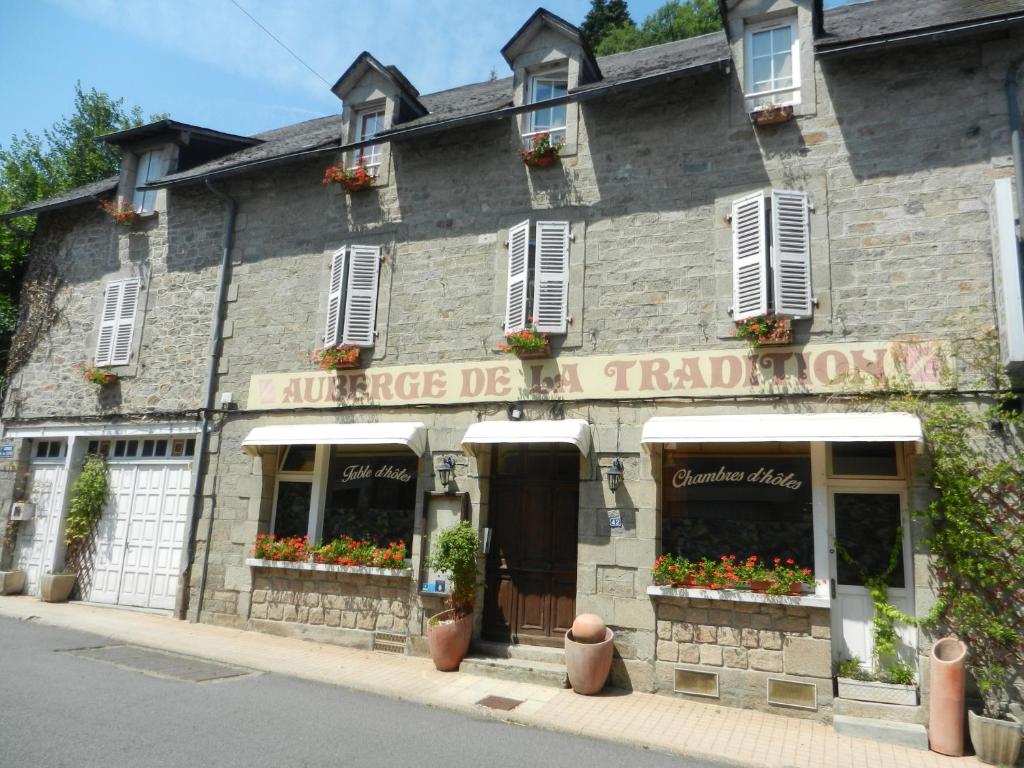un antiguo edificio de piedra con flores en las ventanas en Auberge de la Tradition en Corrèze