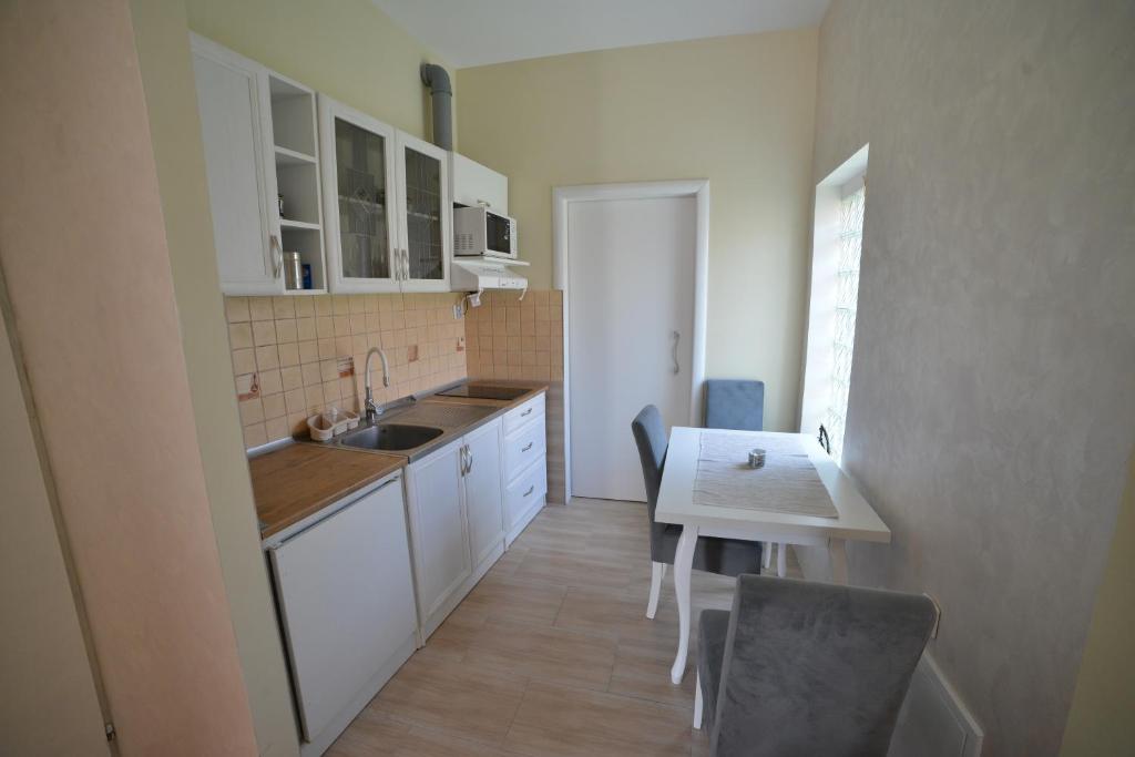 a kitchen with white cabinets and a table and a sink at Apartmani MV in Užice