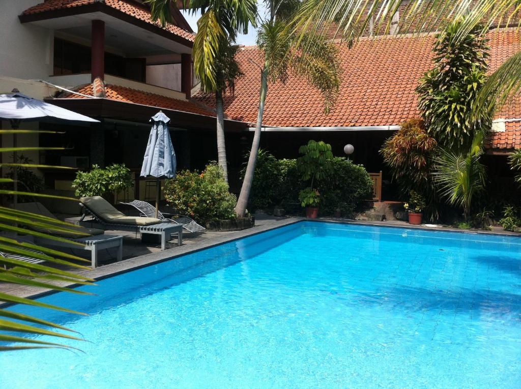 uma grande piscina azul ao lado de uma casa em Harmony Inn em Yogyakarta