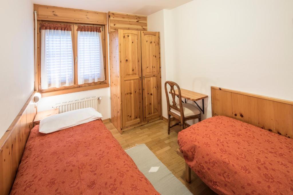 a bedroom with two beds and a table and a chair at Albergo K2 in Madesimo